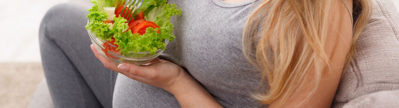 A pregnant woman eating salad