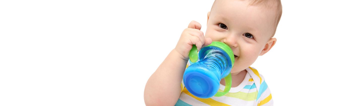 A toddler drinks baby food from Babina out of a cup