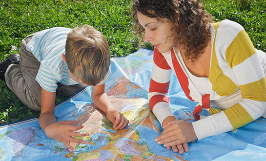 A child looks at a world map with his mother