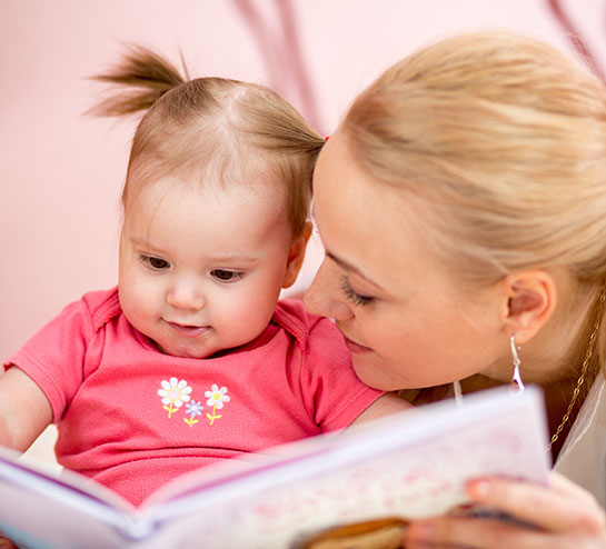 La niña pequeña mira un libro infantil con su mama