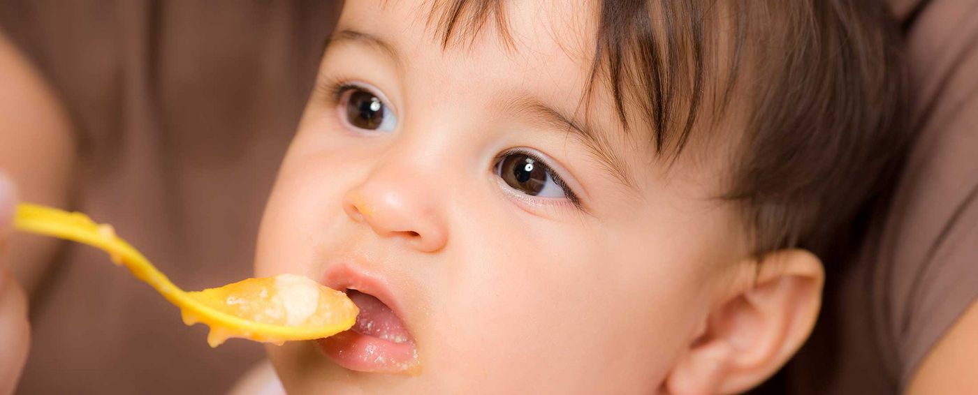 Un niño pequeño recibe una cucharada de papilla para bebés