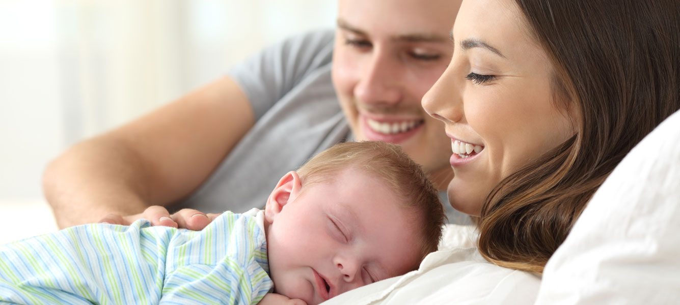 Young family cuddling up with their newborn