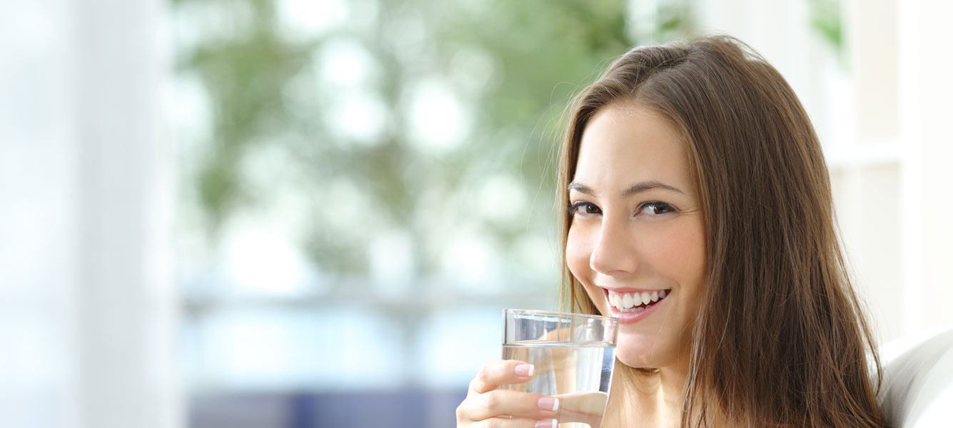 Una mujer joven y atractiva bebiendo un vaso de agua