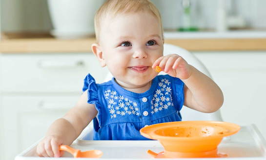 La niña pequeña come gachas de avena