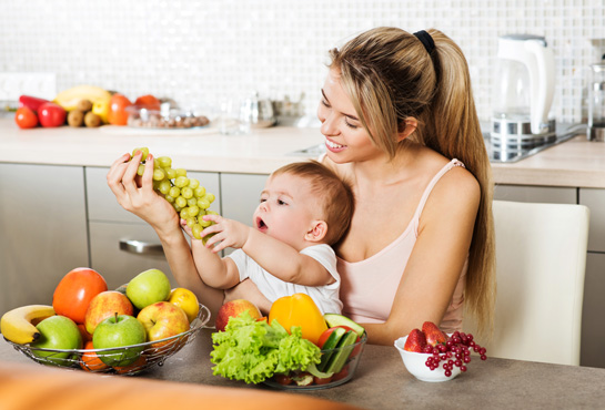 A mother offers grapes to her toddler