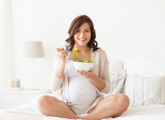 Pregnant woman is eating salad