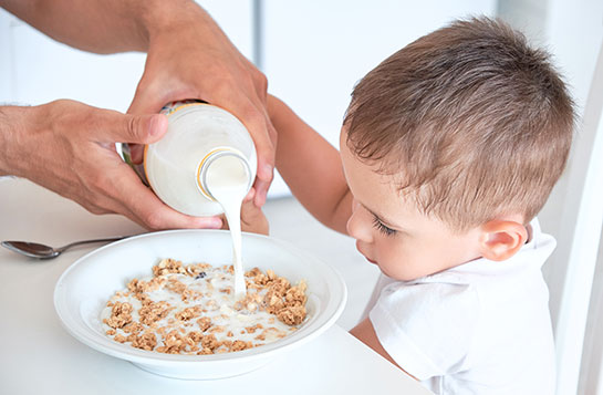 Ein Junge isst Cerealien mit Milch