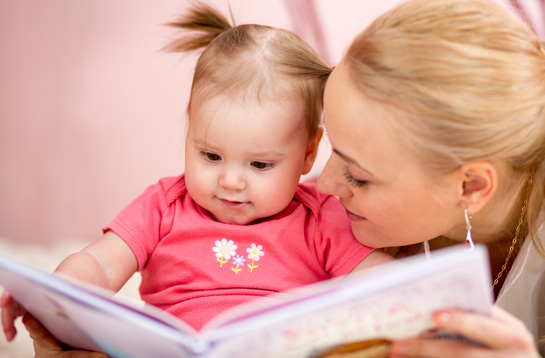 A girl looks at a children's book with her mom